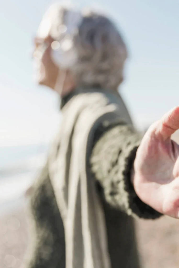 Ältere Frau am Strand mit ausgestreckten Armen